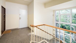 Un escalier propre et bien éclairé, doté d’une rampe en bois, d’une porte et d’une grande fenêtre donnant sur un paysage verdoyant.