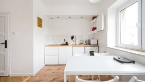 Une cuisine compacte avec des meubles blancs, un plan de travail en bois et une fenêtre qui laisse entrer la lumière naturelle.