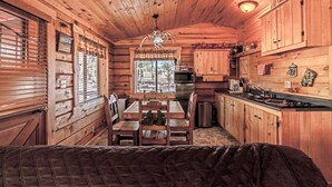 L’intérieur d’une cabane en bois comprend un coin repas, une cuisine et un grand lit.