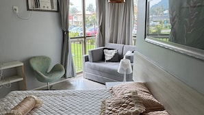 Un dormitorio con cama, una silla, un escritorio y una ventana con cortinas.