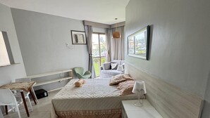 Habitación de hotel con cama, mesita de noche, silla y vistas al exterior.