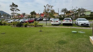 Un estacionamiento con varios coches, un área verde y edificios residenciales al fondo.