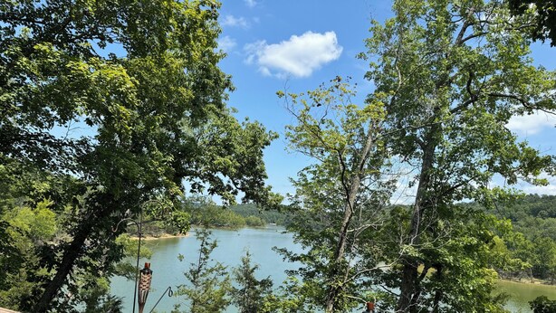 A view of a lake surrounded by trees, with a wooden railing in the foreground. - The Lakeview Cabin (Clarkson)