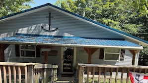 A small house with a blue roof, a wooden porch, and a welcome sign. - The Lakeview Cabin (Clarkson)