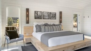 A bedroom with a large bed, a chair, and a window with a view of the outdoors. - Charming 2-bedroom, lakeside cabin at Lake Cypress Springs in Mt. Vernon, TX (Mount Vernon)