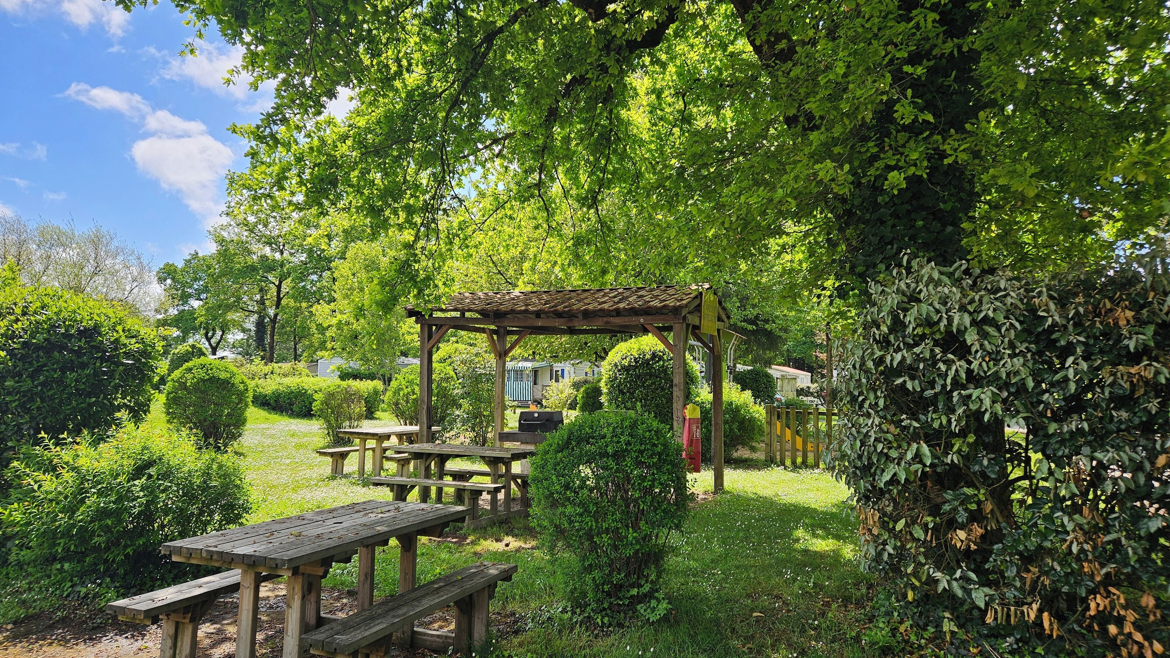 Un jardín con mesas de picnic y un pérgola.