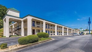 A motel with a central courtyard, multiple balconies, and a parking lot. - HomeTown Inn & Suites (Macon)