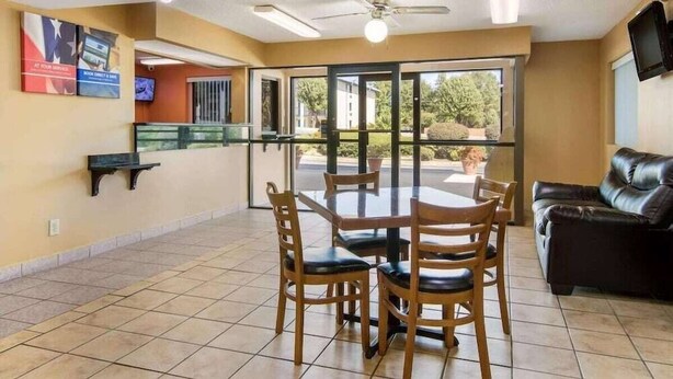 A dining area with a table and chairs, a ceiling fan, and a television on the wall. - HomeTown Inn & Suites (Macon)