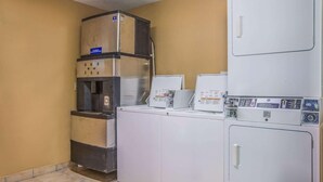 A laundry room with a commercial washer and dryer, a water dispenser, and a small refrigerator. - HomeTown Inn & Suites (Macon)