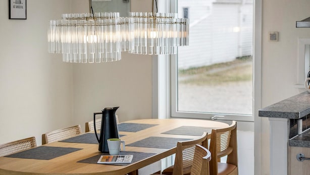 Un comedor con mesa de madera, sillas y una lámpara de araña moderna.
