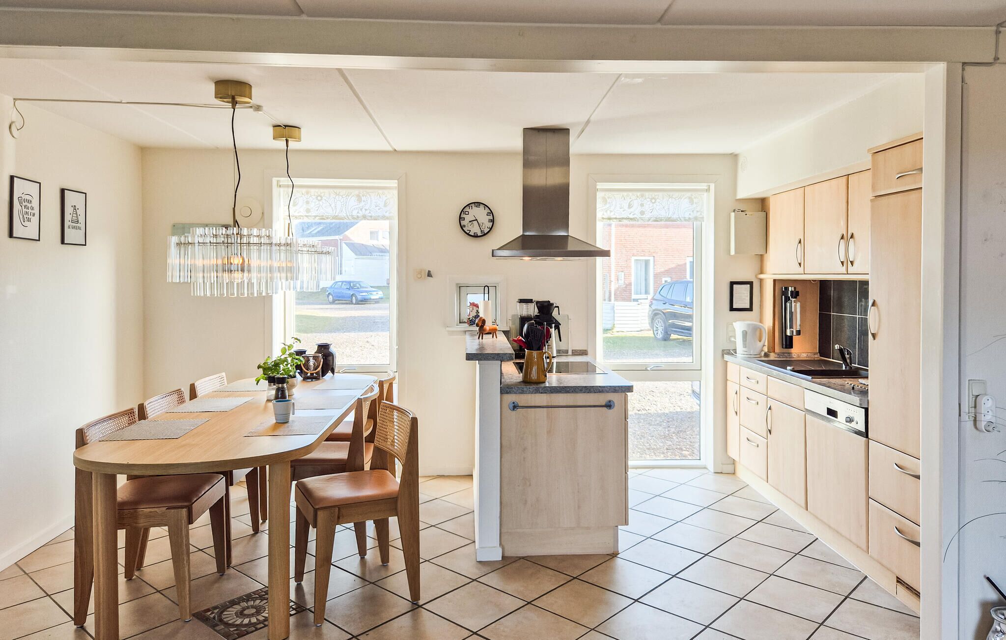 Een moderne keuken met een centraal eiland, houten kastjes en een eethoek met een tafel en stoelen.