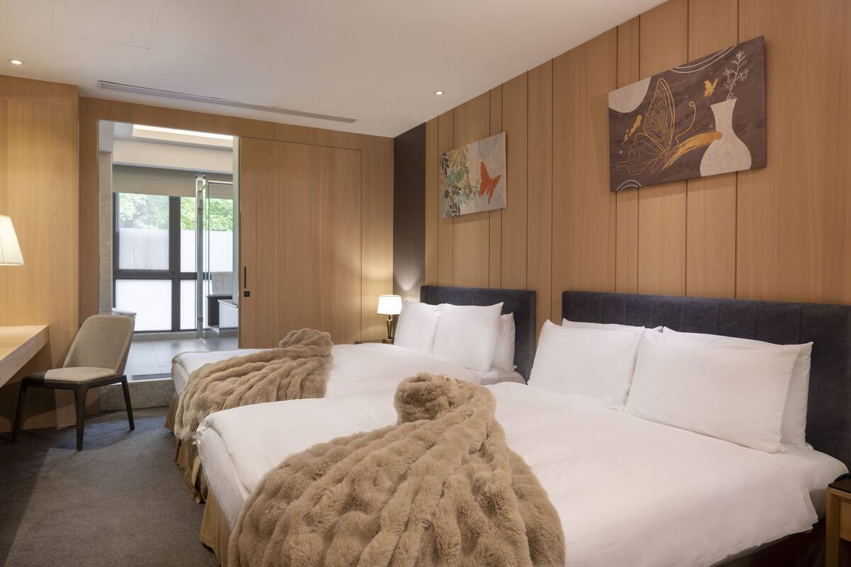 Una habitación de hotel con una cama grande, un escritorio, una silla y un cuadro en la pared.