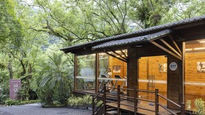 A wooden cabin with a glass door, surrounded by lush greenery. - Butterfly Valley Resort by Cosmos Otium (Wanrong)