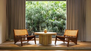 A room with a round wooden table and two wicker chairs, a potted plant on the table, and a view of lush greenery through a large window. - Butterfly Valley Resort by Cosmos Otium (Wanrong)