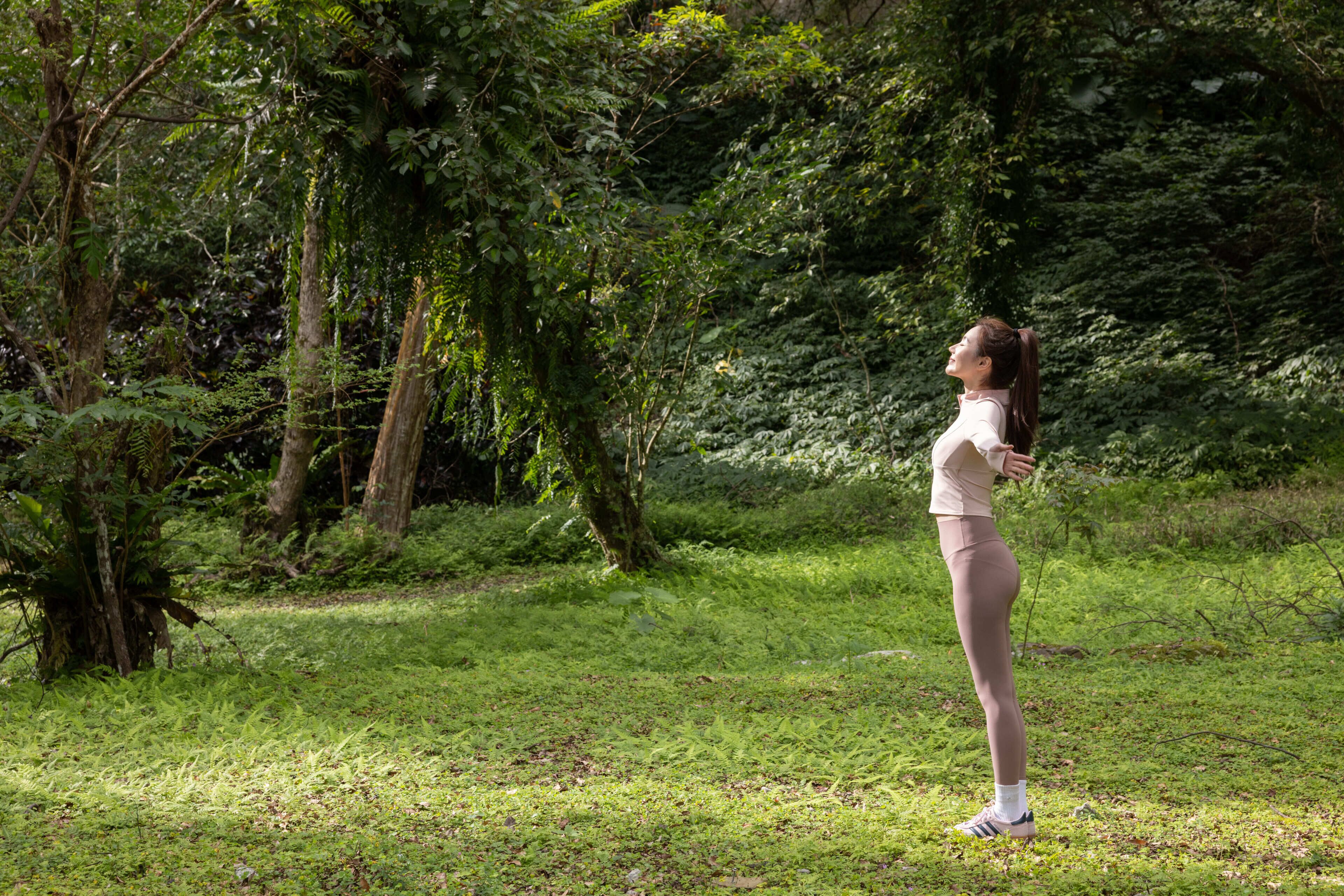 A person standing in a natural setting with trees and grass.