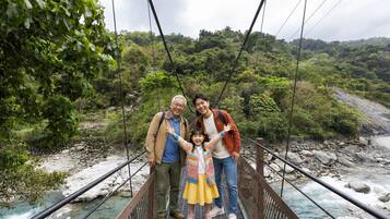 A suspension bridge with a river below, surrounded by greenery.