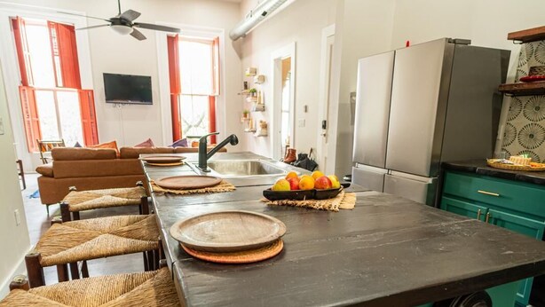 Una cocina moderna con una isla central, sillas de madera y una mesa de comedor.