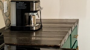 Una cocina con cafetera, una cesta y una pared decorada con un diseño.