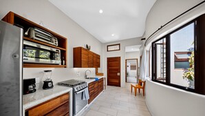 A modern kitchen with built-in appliances, wooden cabinetry, and a view through large windows. - Delightful apartment with AC in Lo de Marcos (Lo de Marcos)