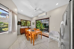 A modern dining area with a wooden table and chairs, a ceiling fan, and a view through large windows. - Delightful apartment with AC in Lo de Marcos (Lo de Marcos)