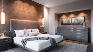 A modern bedroom with a large bed, a nightstand, a dresser, and a wall-mounted painting.