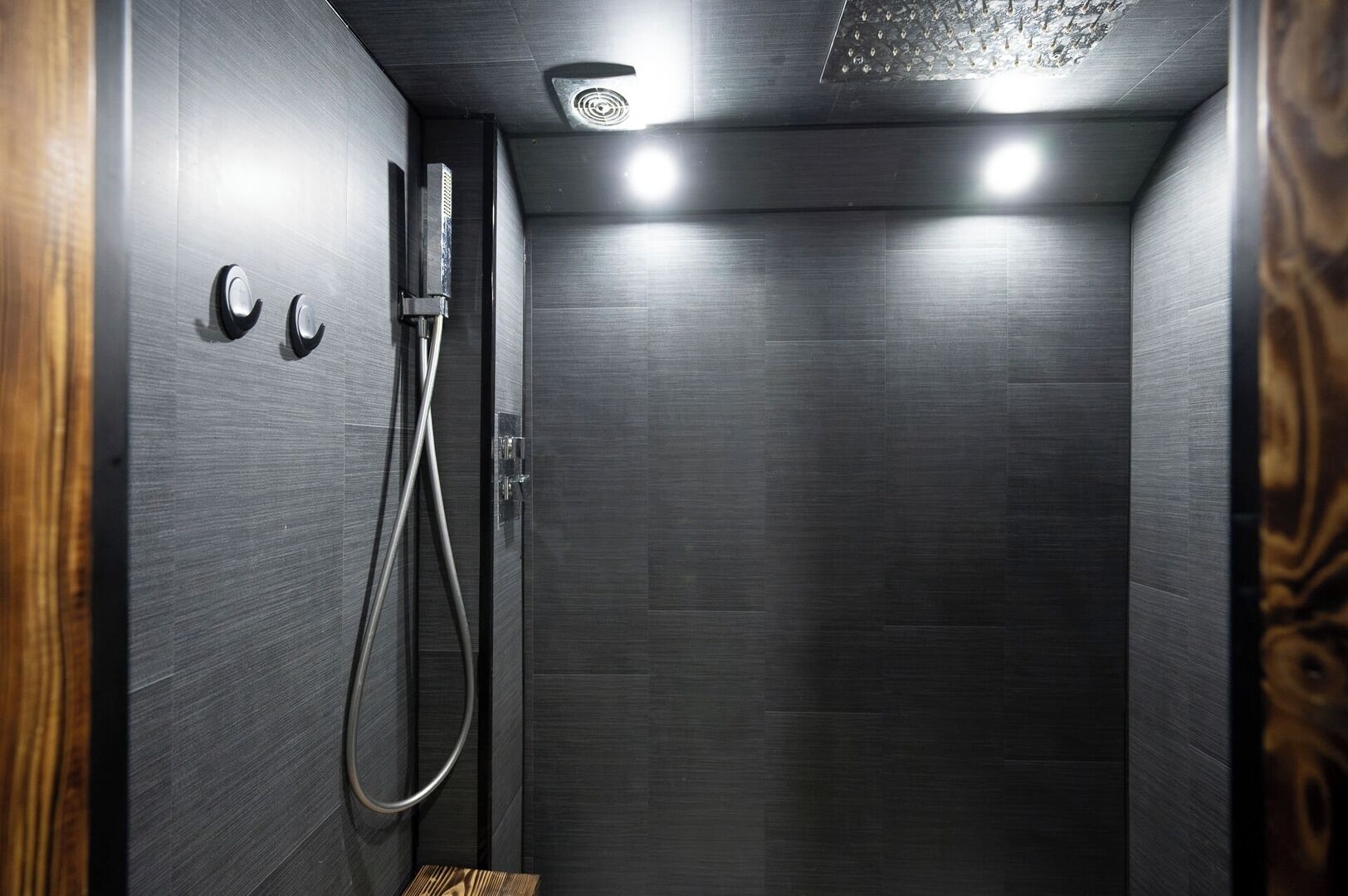 Een moderne douche met een handdouche en bedieningspaneel aan de muur.