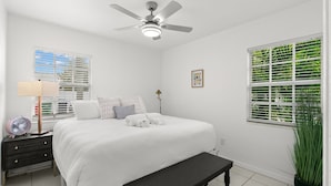 A bedroom with a bed, bedside table, lamp, fan, and a window with blinds. - 3401 W San Juan St Tampa FL 33629 USA (Tampa)