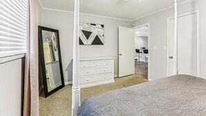Un dormitorio con cama, cómoda, espejo y ventilador de techo.