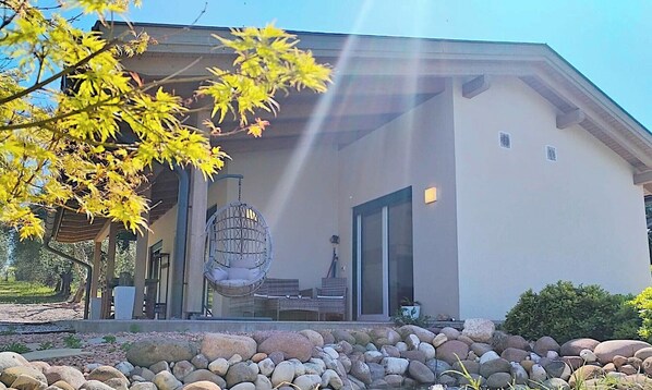 Un edificio moderno con un portico coperto, un lampadario sospeso e un vialetto in pietra che conduce all'ingresso.