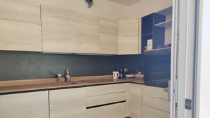 Une cuisine moderne avec des meubles de couleur bois clair, un revêtement mural foncé et un four encastré.