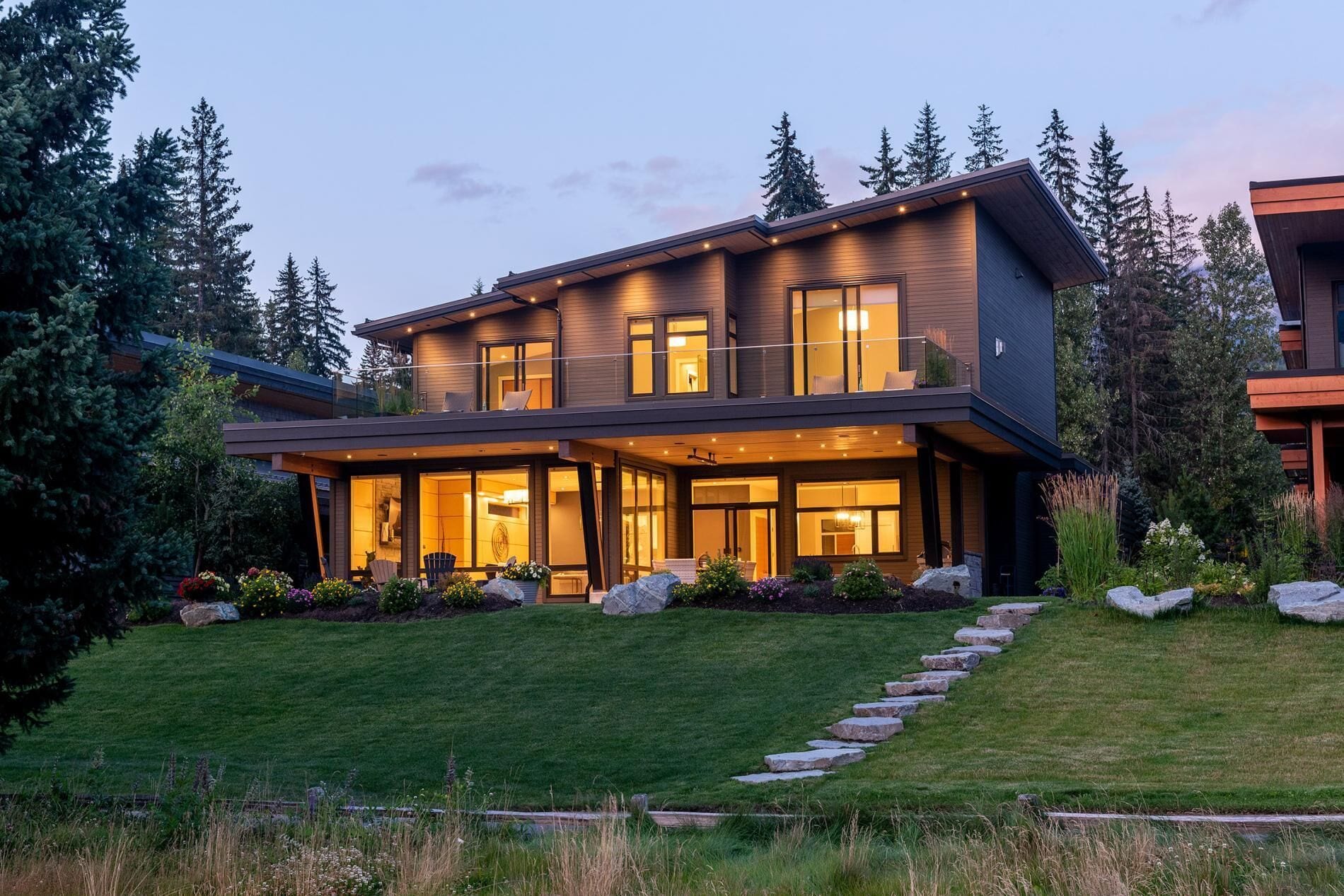 A modern two-story house with large windows and a covered patio area.