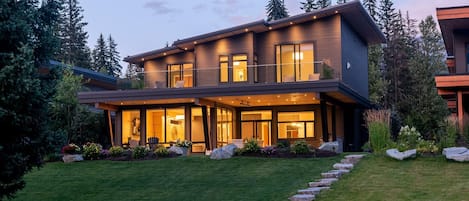 A modern two-story house with large windows and a covered patio area.