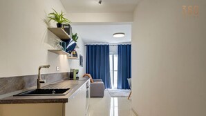 Eine moderne Küche mit integriertem Spülbecken, einer Arbeitsplatte und einem Blumentopf. Ein Fenster mit blauen Vorhängen bietet einen Ausblick ins Freie.