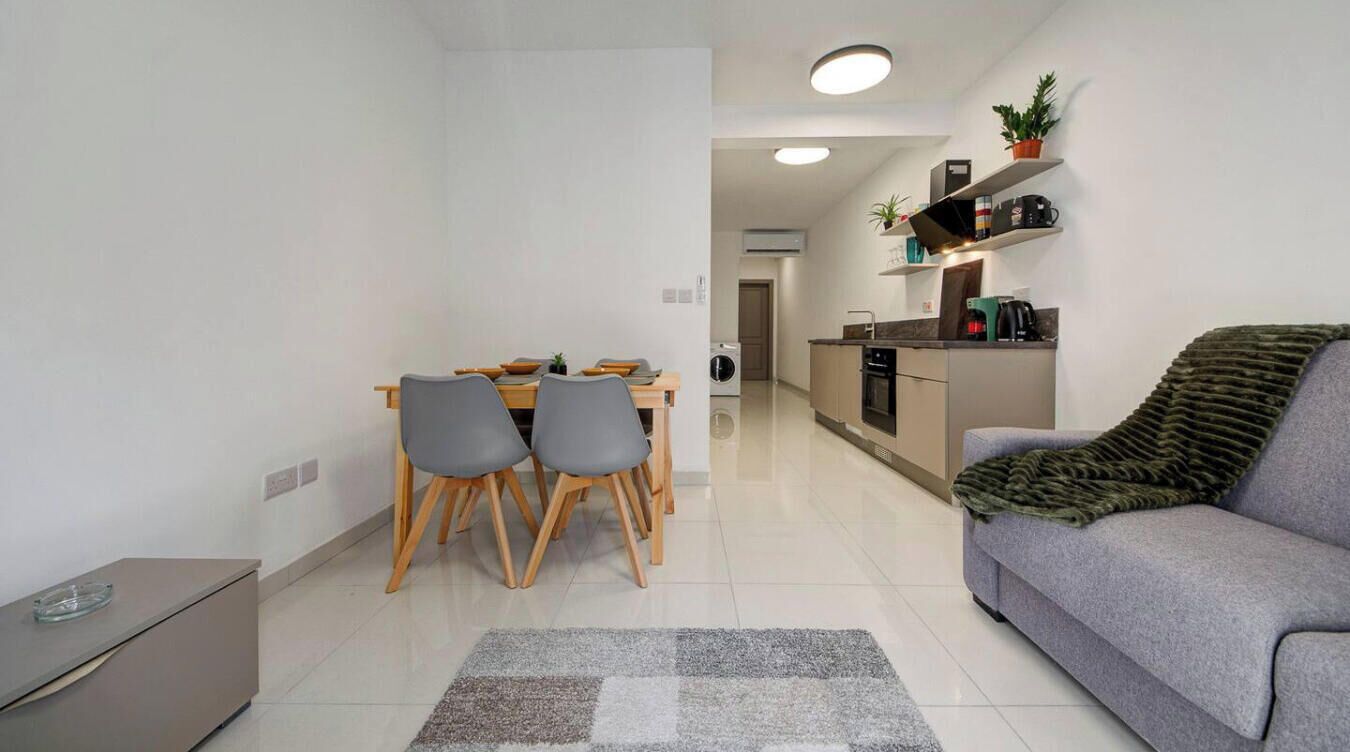 Un apartamento moderno con comedor, kitchenette y sala de estar con sofá y alfombra.