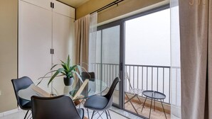 Un apartamento moderno con balcón, una mesa de comedor de vidrio y sillas negras.