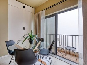 Eine moderne Wohnung mit Balkon, einem Glastisch und schwarzen Stühlen.