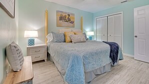 Une chambre à coucher avec un lit, des tables de chevet, un ventilateur de plafond, un tableau et un placard.