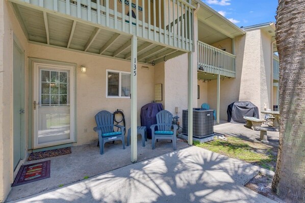 A two-story building with a covered porch, outdoor seating, and a grill area.
