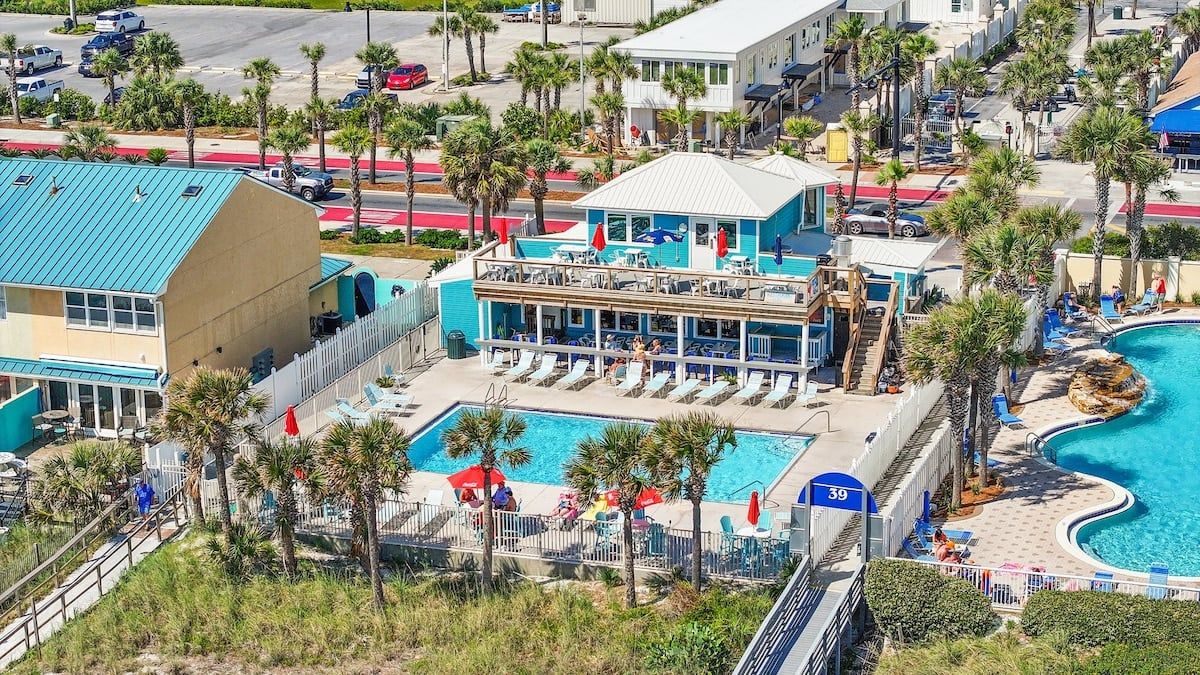 Un hôtel doté d’une piscine, d’un espace détente couvert et d’un bâtiment avec un toit bleu.