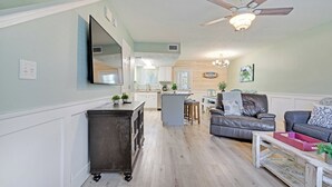 Een ruime woonkamer met een open haard, een eethoek en een keuken op de achtergrond.
