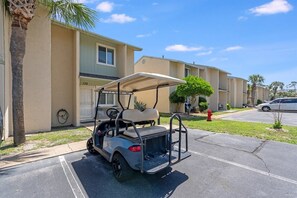 Un carrito de golf estacionado en un estacionamiento, con un edificio al fondo.