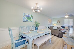 A dining area with a table set for four, a bench, and a sofa in the background.