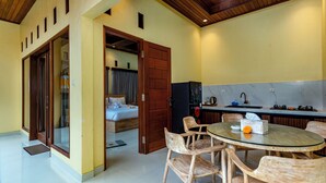 Een hotelkamer met een bed, een zithoek met tafel en stoelen, een keuken met spoelbak en fornuis, en een badkamer met douche.