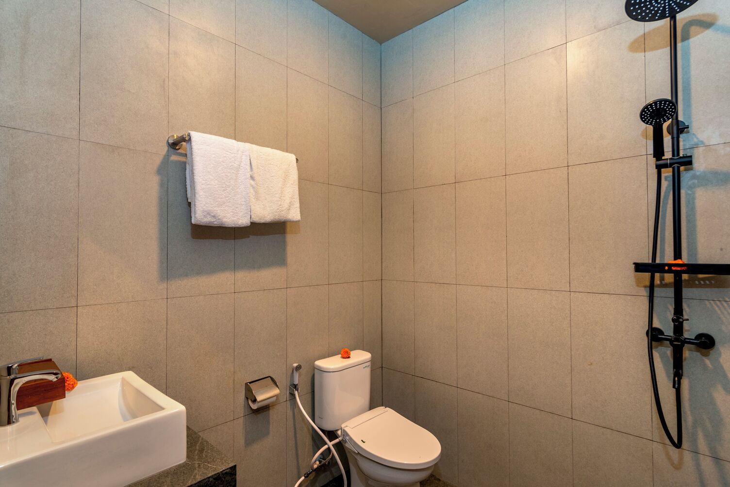 A modern bathroom with a white sink, toilet, and shower.