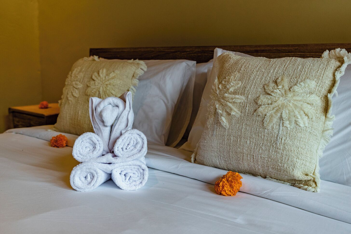 A neatly made bed with rolled towels and decorative pillows.
