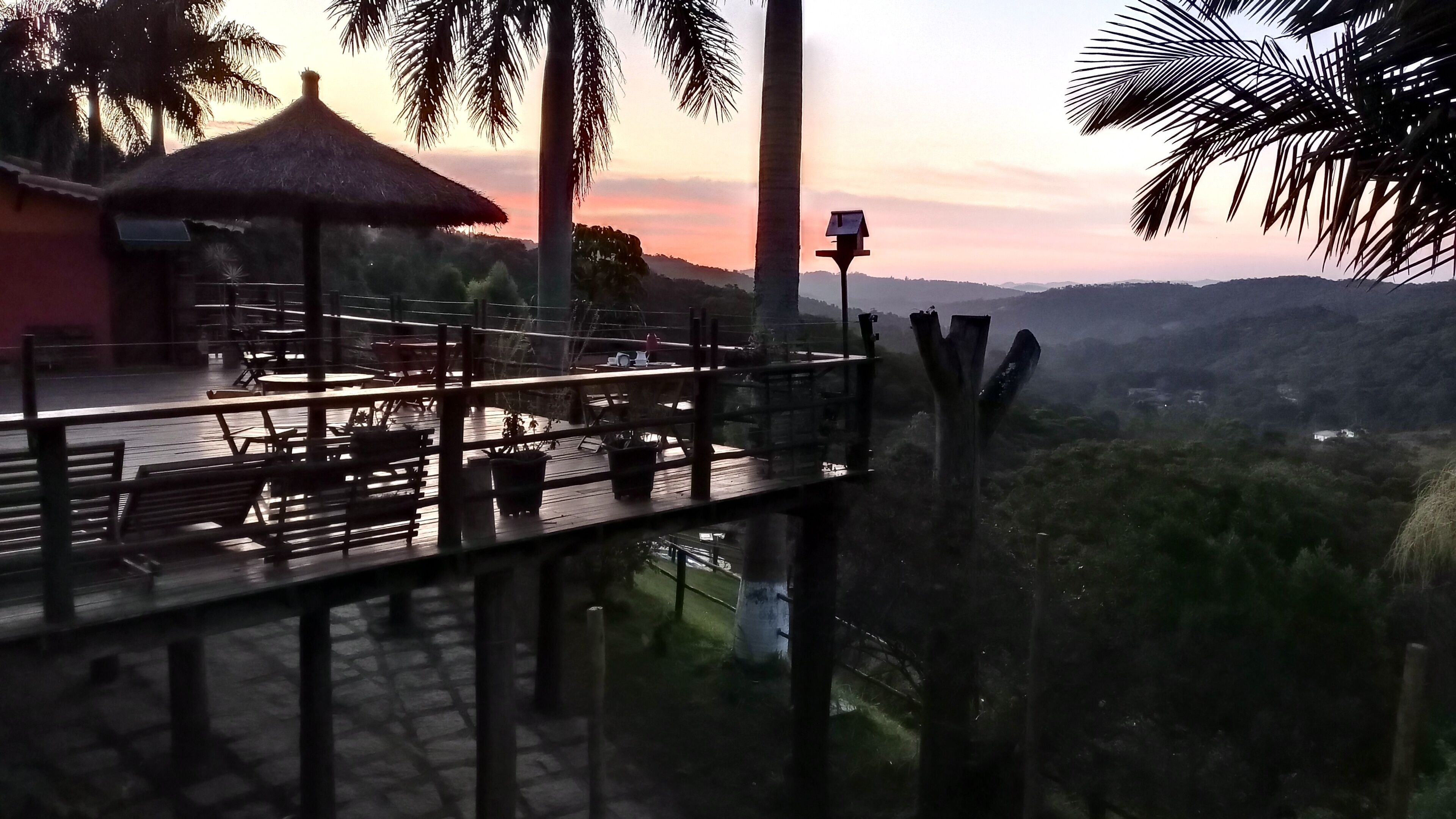 A terrace with tables and chairs, overlooking a hilly landscape.