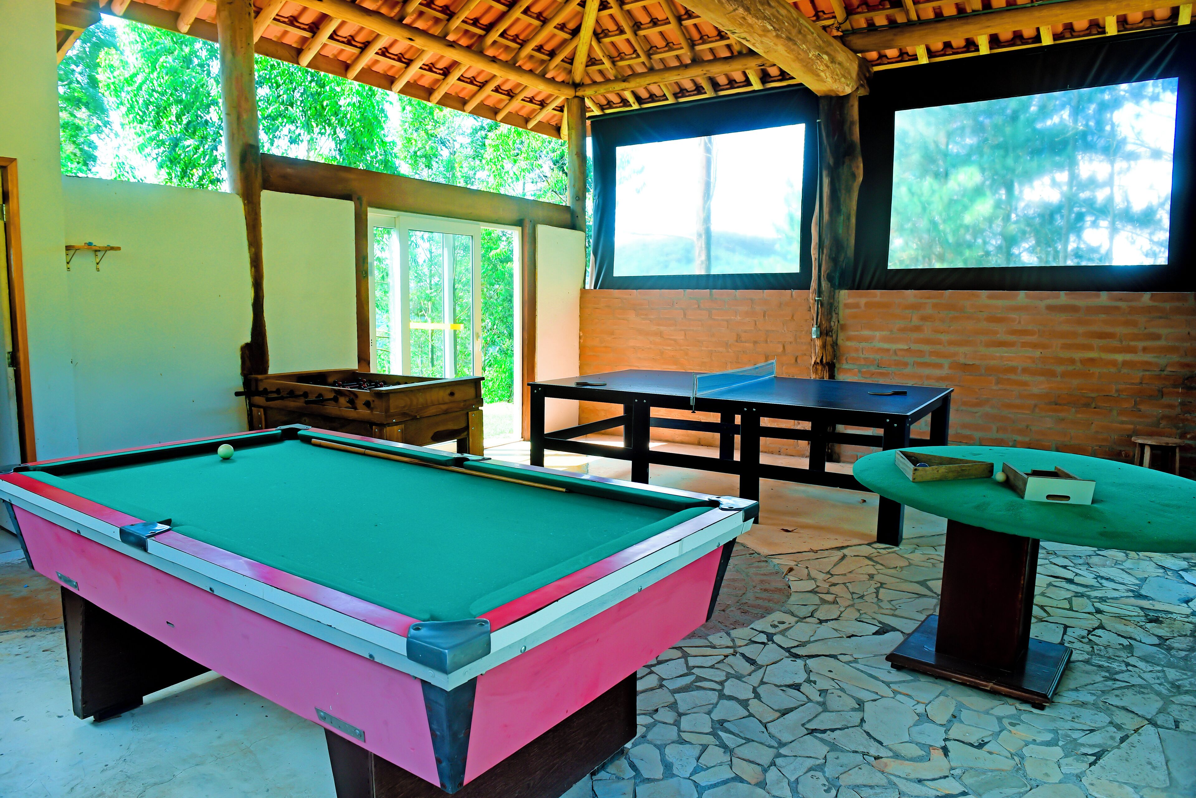 A pool table with a green felt surface, a billiards table, and a small table with a green top.