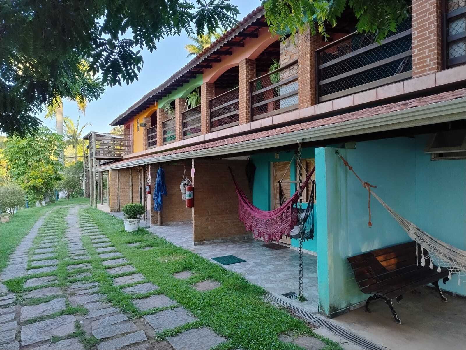 A two-story house with a covered porch, a hammock, and a pathway leading to the entrance.