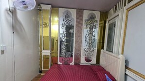 Ein Schlafzimmer mit Bett, Sessel, Ventilator und dekorativen Wandverkleidungen.