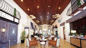 A spacious lobby with a high ceiling, wooden paneling, and a central seating area with chairs and a round table. - Disney Getaway 6BR | Theater + Game Room (Kissimmee)